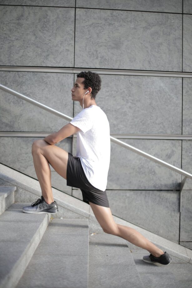 Millennial male athlete stretching on stairs in urban setting, symbolizing discipline, consistency, and daily systems for success.