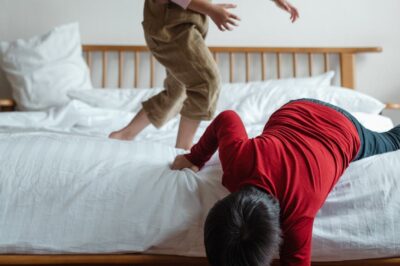 "Happy little brother and sister playing on bed, sharing a joyful sibling moment"