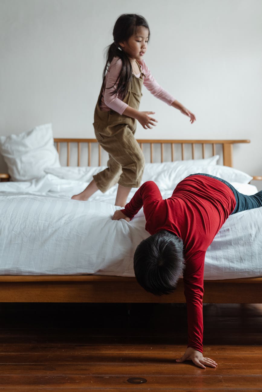 "Happy little brother and sister playing on bed, sharing a joyful sibling moment"